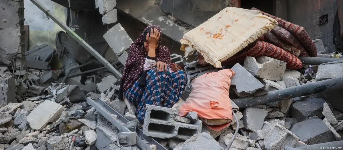 Una mujer llora sentada sobre los escombros de su casa, destruida por un ataque israelí, en el campo de refugiados de Nuseirat, en el centro de la Franja de Gaza. Foto: DW